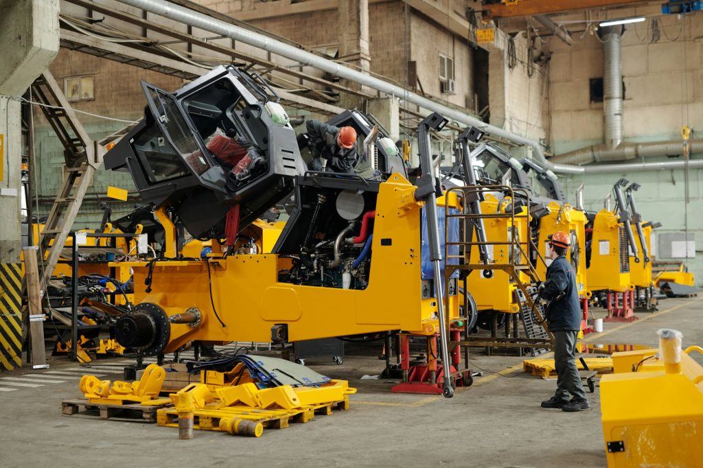 Male workers of industrial plant or repairmen checking efficiency of machines